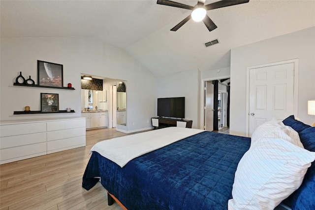 bedroom featuring ceiling fan, connected bathroom, vaulted ceiling, and light hardwood / wood-style flooring