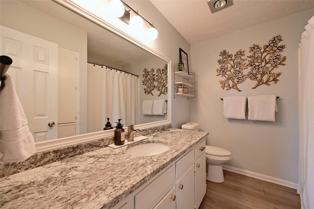 bathroom with vanity, hardwood / wood-style flooring, toilet, and a textured ceiling