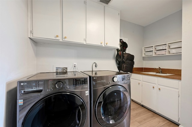 laundry area with washer and dryer, sink, cabinets, and light hardwood / wood-style flooring