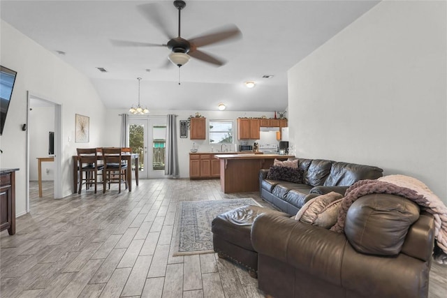 living room featuring lofted ceiling and ceiling fan with notable chandelier