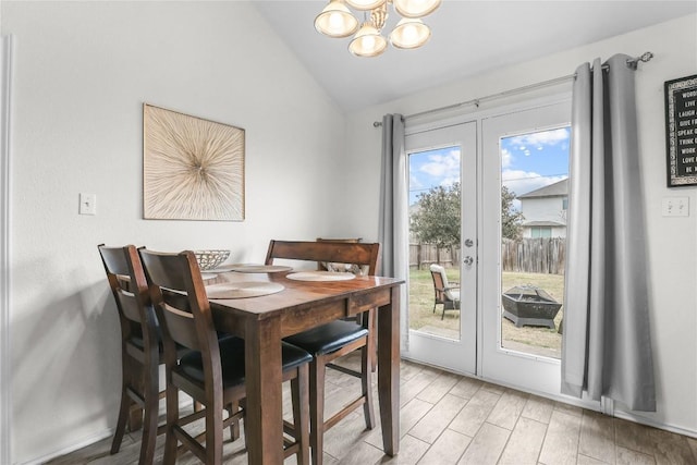 dining space with hardwood / wood-style flooring, vaulted ceiling, french doors, and a chandelier