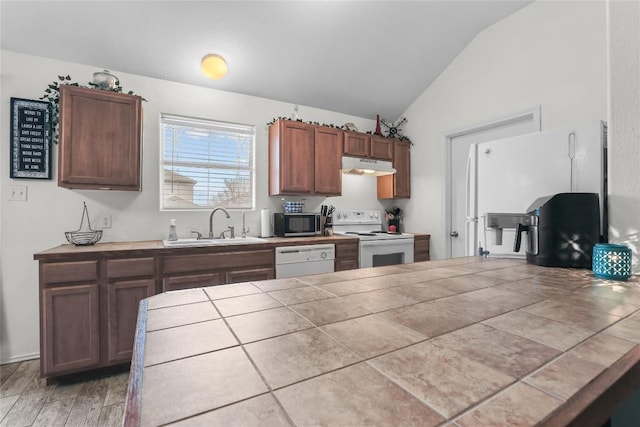 kitchen with sink, white appliances, hardwood / wood-style flooring, tile counters, and vaulted ceiling