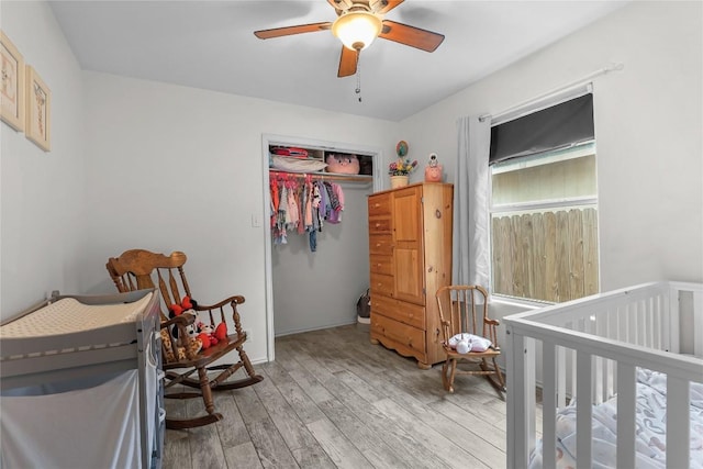 bedroom with hardwood / wood-style flooring, a nursery area, a closet, and ceiling fan