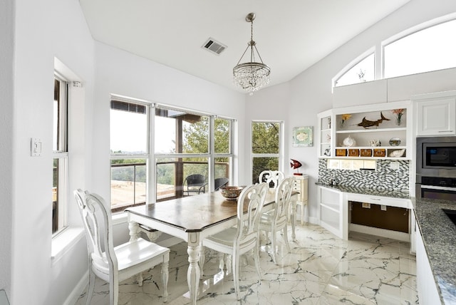 dining area with baseboards, visible vents, lofted ceiling, marble finish floor, and an inviting chandelier