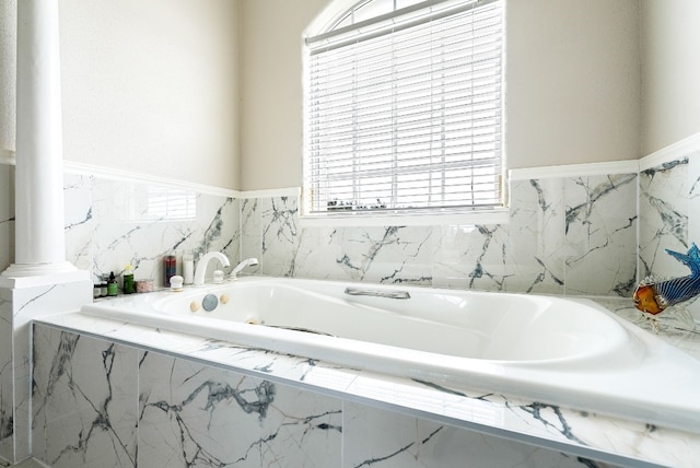 full bath with decorative columns and a bath