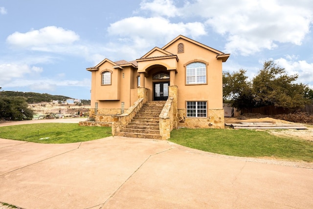 mediterranean / spanish-style home featuring stairs, a front yard, french doors, and stucco siding