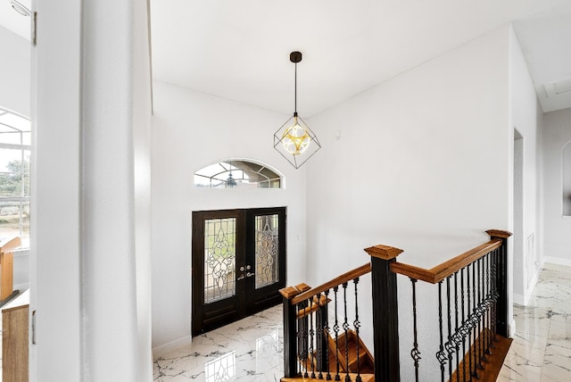 foyer entrance featuring marble finish floor, french doors, and baseboards