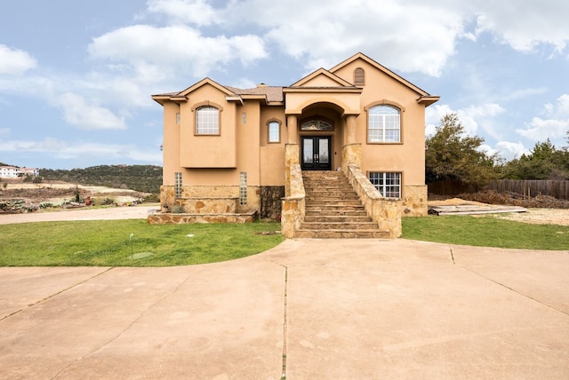 view of front of property with stairs, french doors, a front lawn, and stucco siding