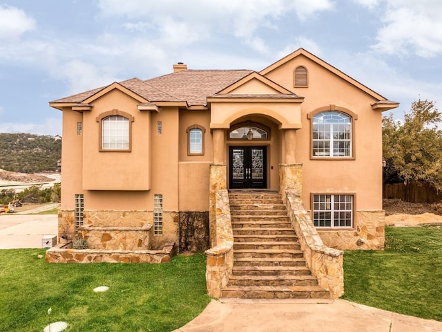 mediterranean / spanish-style house featuring french doors, a chimney, stucco siding, stairway, and a front yard