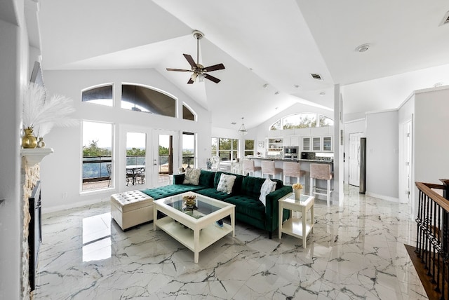 living room with ceiling fan, high vaulted ceiling, a stone fireplace, visible vents, and marble finish floor