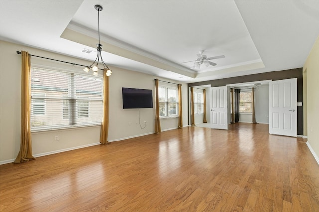 unfurnished living room with light hardwood / wood-style flooring, ceiling fan, and a tray ceiling