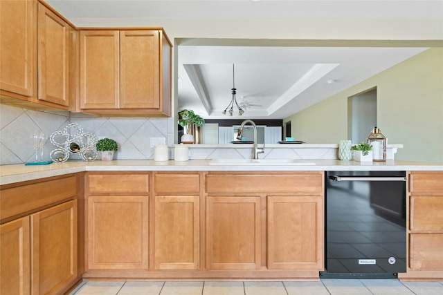 kitchen with light tile patterned flooring, tasteful backsplash, dishwasher, sink, and a tray ceiling