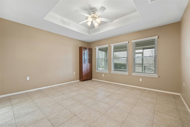 tiled spare room featuring crown molding, a tray ceiling, and ceiling fan