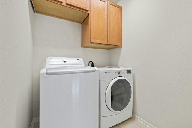 laundry area featuring cabinets, washer and clothes dryer, and light tile patterned floors