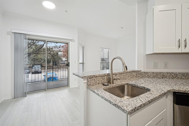 kitchen with a wealth of natural light, white cabinets, a sink, and dishwasher