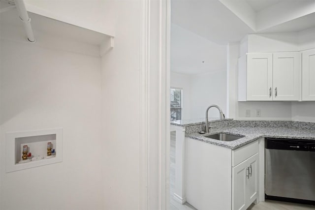 kitchen featuring a peninsula, a sink, white cabinetry, stainless steel dishwasher, and light stone countertops