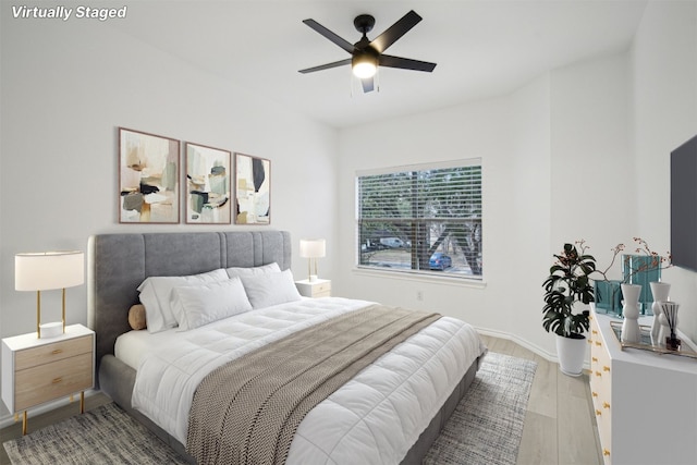 bedroom featuring light wood finished floors, baseboards, and a ceiling fan