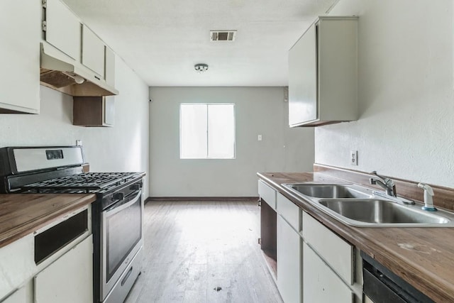 kitchen featuring sink, appliances with stainless steel finishes, butcher block counters, white cabinets, and light wood-type flooring