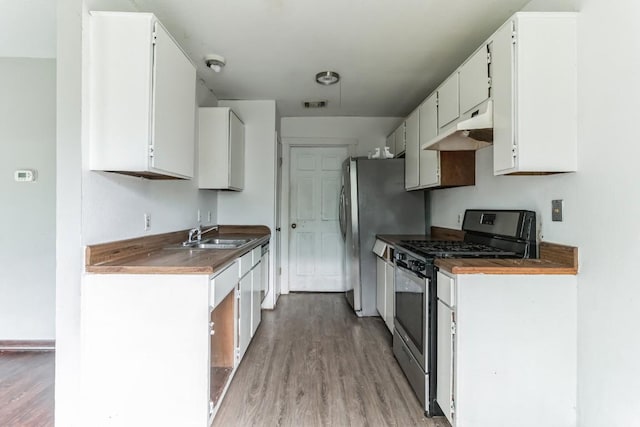 kitchen featuring stainless steel appliances, sink, white cabinets, and light wood-type flooring