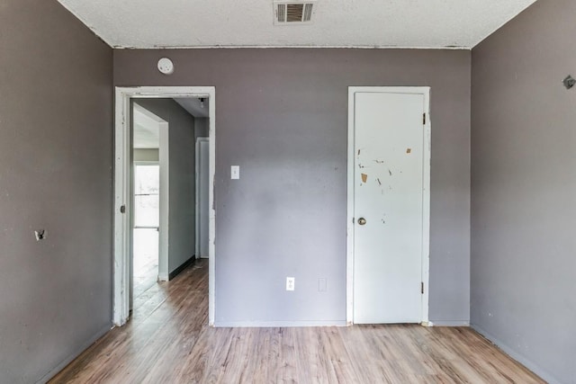 spare room featuring a textured ceiling and light wood-type flooring