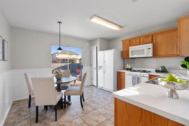 kitchen with light tile patterned flooring, white appliances, and decorative light fixtures