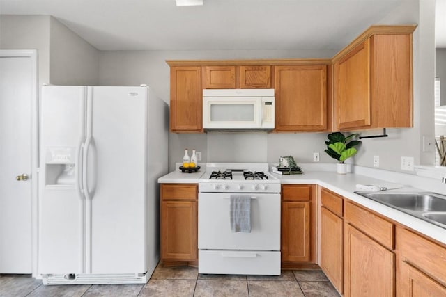 kitchen featuring light tile patterned floors, white appliances, and sink