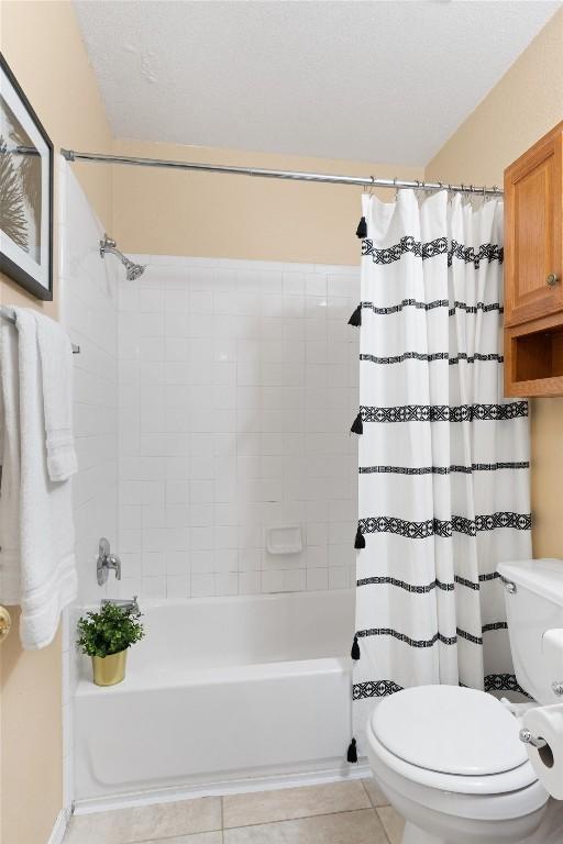 bathroom featuring tile patterned flooring, shower / bath combination with curtain, and toilet