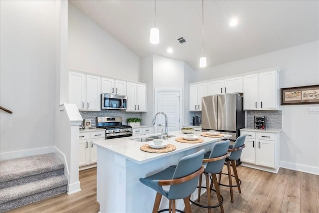 kitchen with sink, appliances with stainless steel finishes, white cabinetry, high vaulted ceiling, and decorative light fixtures