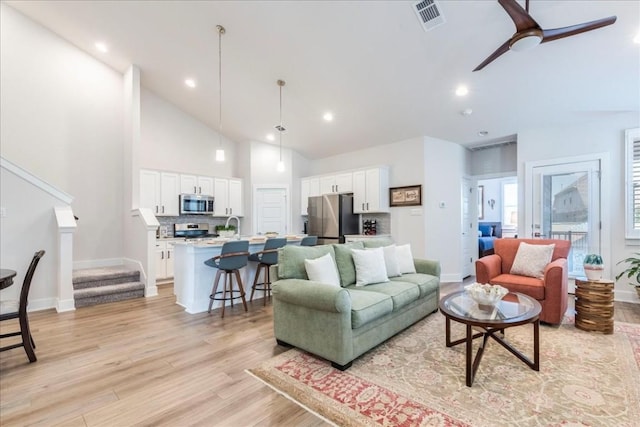 living room featuring ceiling fan, sink, high vaulted ceiling, and light hardwood / wood-style floors