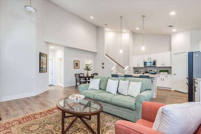 living room with high vaulted ceiling and light hardwood / wood-style flooring