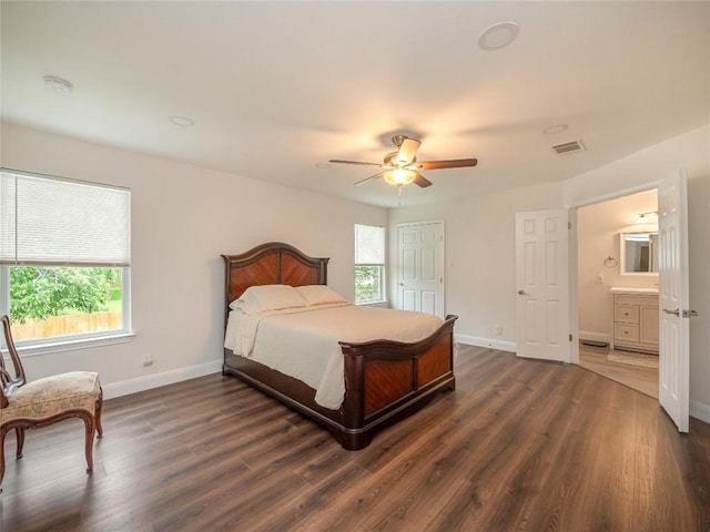 bedroom with dark wood-type flooring, ceiling fan, connected bathroom, and multiple windows