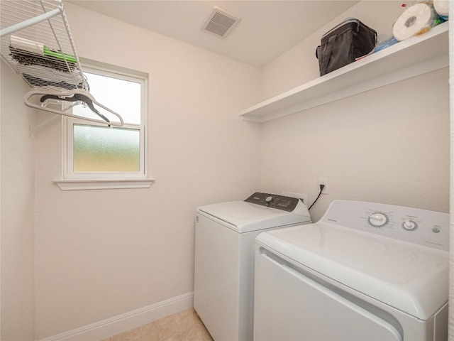 clothes washing area featuring washer and clothes dryer and light tile patterned floors