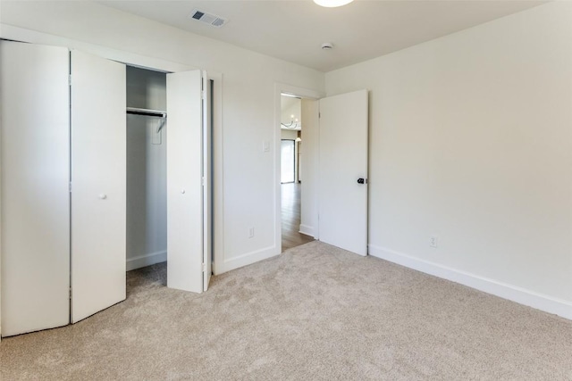 unfurnished bedroom with light carpet and a closet