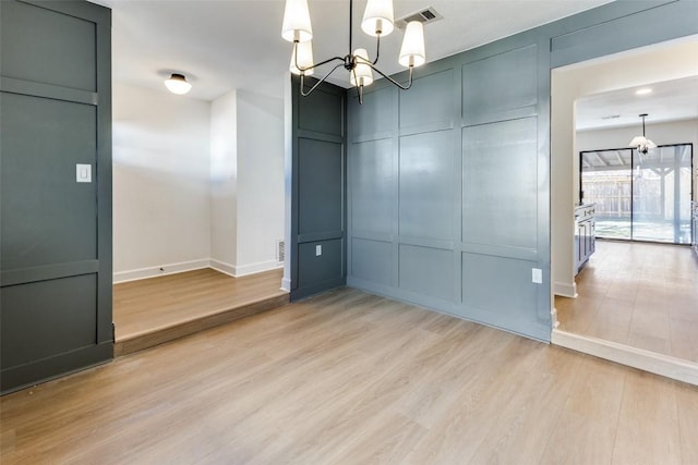 spare room featuring an inviting chandelier and light wood-type flooring