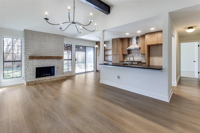 kitchen with vaulted ceiling with beams, decorative light fixtures, hardwood / wood-style floors, decorative backsplash, and wall chimney range hood