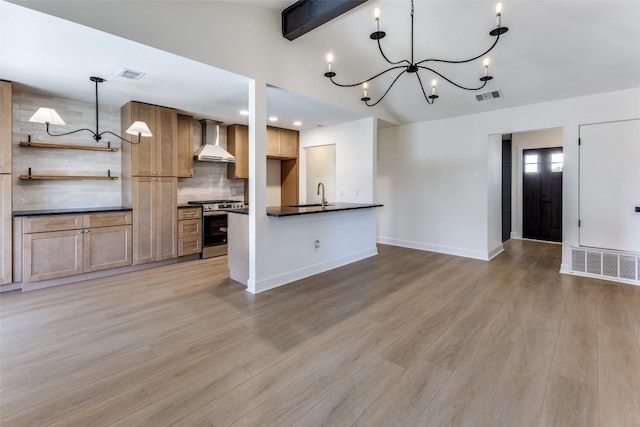 kitchen featuring hanging light fixtures, gas range, a chandelier, and wall chimney exhaust hood