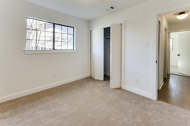 unfurnished bedroom featuring light carpet and a closet