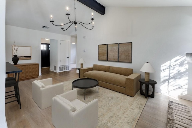 living room with vaulted ceiling with beams, light hardwood / wood-style flooring, and a chandelier