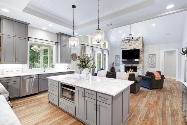 3975 Fm 3158, Dale, TX 78616 - kitchen featuring pendant lighting, appliances with stainless steel finishes, gray cabinetry, a tray ceiling, and light wood-type flooring