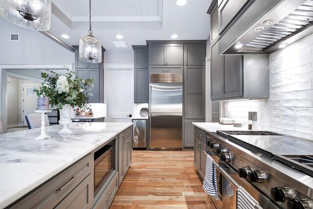 3975 Fm 3158, Dale, TX 78616 - kitchen featuring built in appliances, tasteful backsplash, ornamental molding, a raised ceiling, and wall chimney exhaust hood