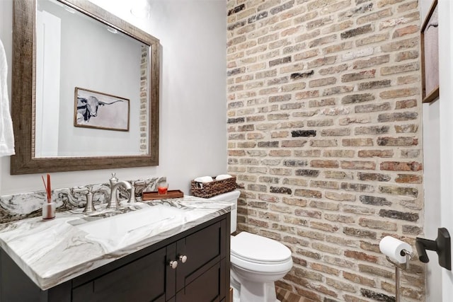 3975 Fm 3158, Dale, TX 78616 - bathroom featuring brick wall, toilet, and vanity