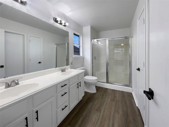 bathroom with vanity, hardwood / wood-style floors, a shower with shower door, and toilet