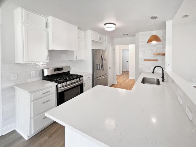 1406 Rio Bravo Loop, Leander, TX 78641 - kitchen with stainless steel appliances, light wood-style floors, white cabinets, tasteful backsplash, and a peninsula