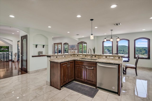 kitchen with sink, hanging light fixtures, dishwasher, a large island, and light stone countertops