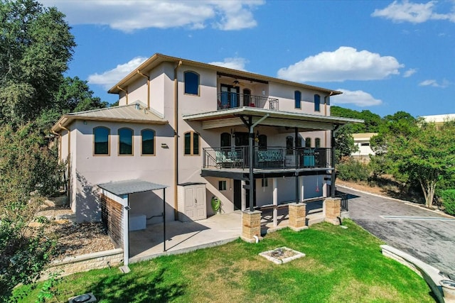 rear view of house with a patio, a balcony, and a yard