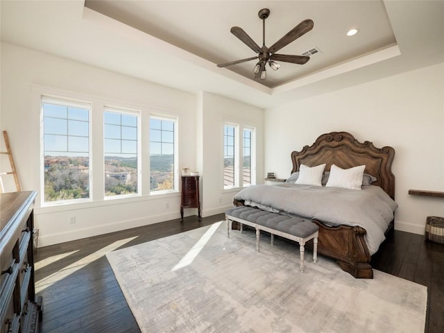 bedroom featuring ceiling fan, dark hardwood / wood-style floors, and a raised ceiling