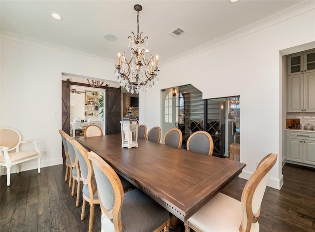 dining room featuring crown molding, dark wood-type flooring, a barn door, and a chandelier