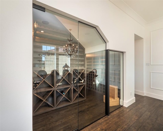 wine cellar with dark wood-type flooring, crown molding, and a chandelier