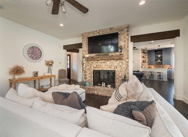 living room featuring ceiling fan, dark hardwood / wood-style flooring, and a brick fireplace