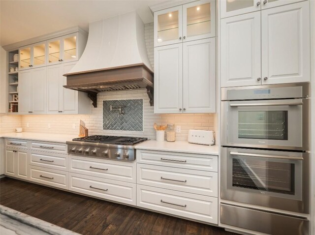 kitchen featuring premium range hood, white cabinetry, appliances with stainless steel finishes, dark hardwood / wood-style floors, and decorative backsplash